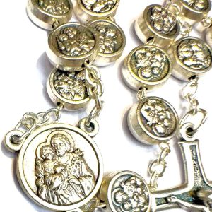 Rosario metálico plateado con medallas en relieve y crucifijo sobre superficie blanca
